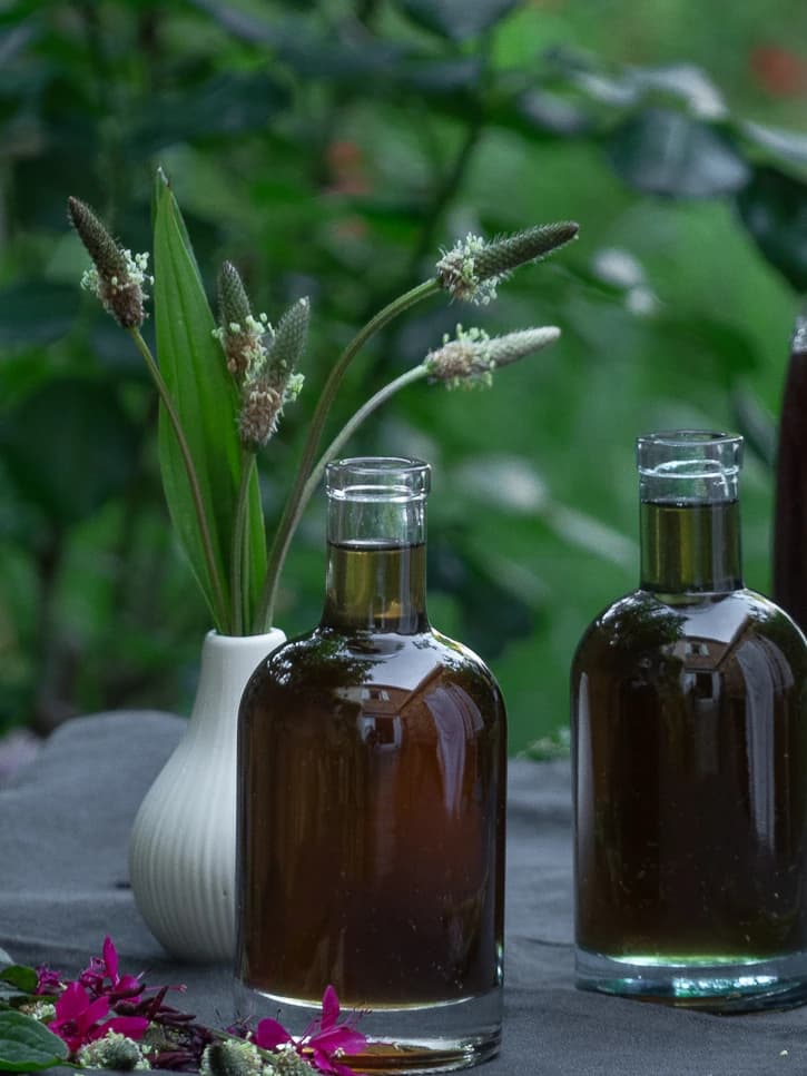 2 flacons de sirop de plantain avec la nature en fond